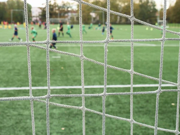 Młoda drużyna piłki nożnej na placu zabaw oglądana przez sieć — Zdjęcie stockowe