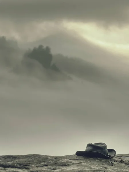 ブラックレザーカウボーイハットは霧の国の上のピークに横たわっています — ストック写真
