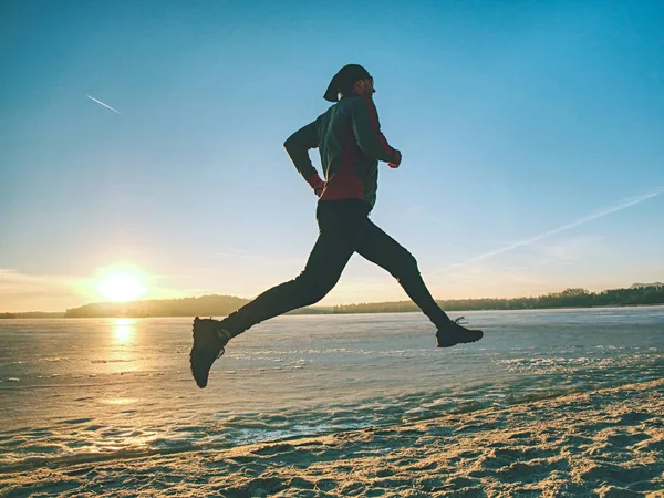 Temporada de invierno y concepto saludable - hombre corriendo a lo largo del lago —  Fotos de Stock