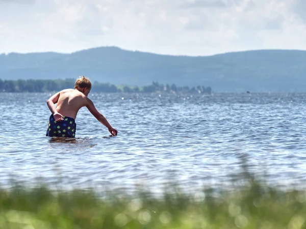 少年は膝の下で水とテスト温度で湖に滞在 — ストック写真
