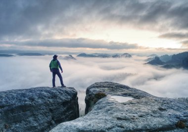 İnsanoğlu sonunda kayanın üzerinde duruyor ve sisli dağ manzarasının tadını çıkarıyor. 