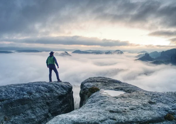 Человек Финнелли стоит на скале и наслаждается туманным видом на горы — стоковое фото