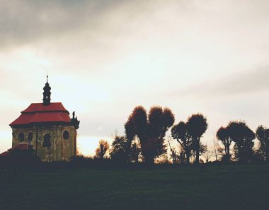 Tepede eski kireç ağaçları olan bir kilise. Karanlık çayırlar 
