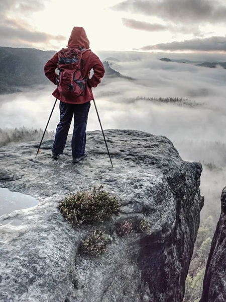 Wędrowiec z czerwonym plecakiem i kijami trekkingowymi na krawędzi — Zdjęcie stockowe
