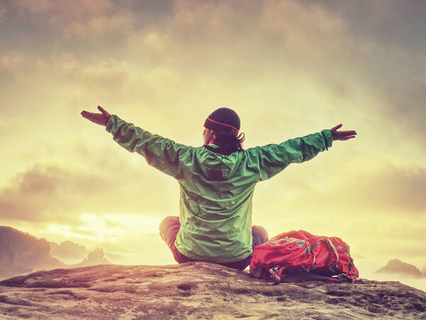 Young woman sit down on top of mountain celebrate day