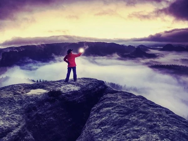 Ragazza sul bordo roccioso sopra la nube nebbiosa illuminato mondo nebbioso — Foto Stock