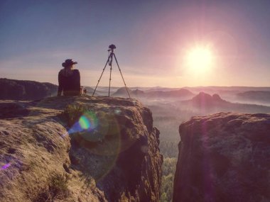 Kadın fotoğrafçı manzaranın fotoğrafını çektikten sonra dinleniyor.