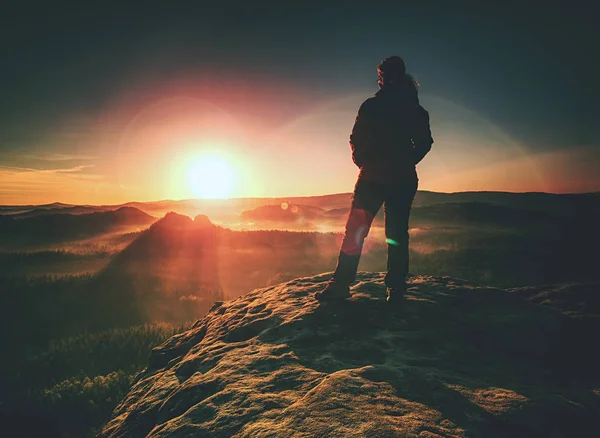 Young woman walks on hill above mist. Strong daybreak sun — ストック写真