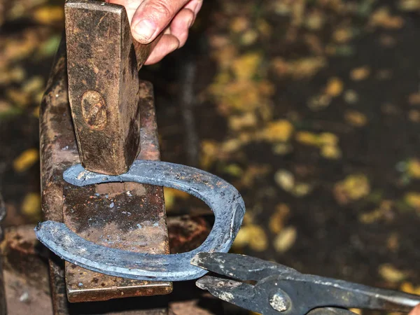 Abile fabbro uomo colpire un rosso caldo ferro di cavallo sul incudine . — Foto Stock