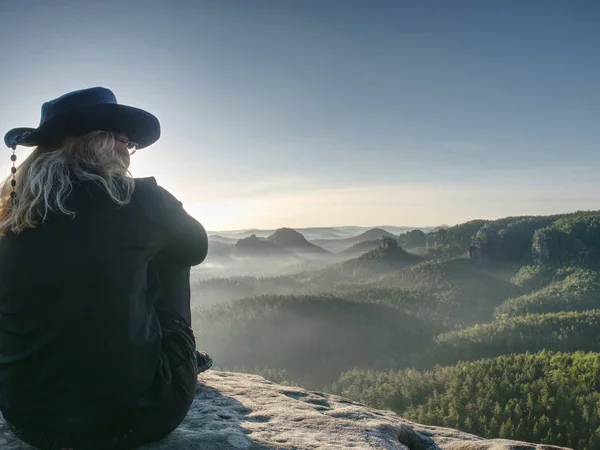 Красивый турист, сидящий на краю горы и наслаждающийся видом — стоковое фото