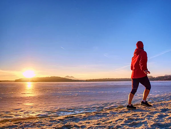Entrenamiento regular de invierno. Correr por el río congelado en la playa de arena — Foto de Stock
