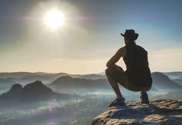 Людина відпочиває на вершині високий пік, дивлячись на захід сонця — стокове фото