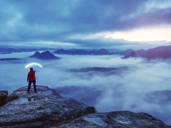 Девушка-путешественница стоит на вершине горы держа сильный свет — стоковое фото