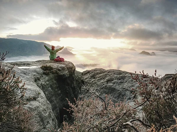 Freundin sitzt mit erhobenen Händen auf nebligem Sonnenaufgang — Stockfoto