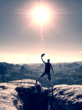 Gün batımını dağlarda kutlayan kolları açık bir adam.