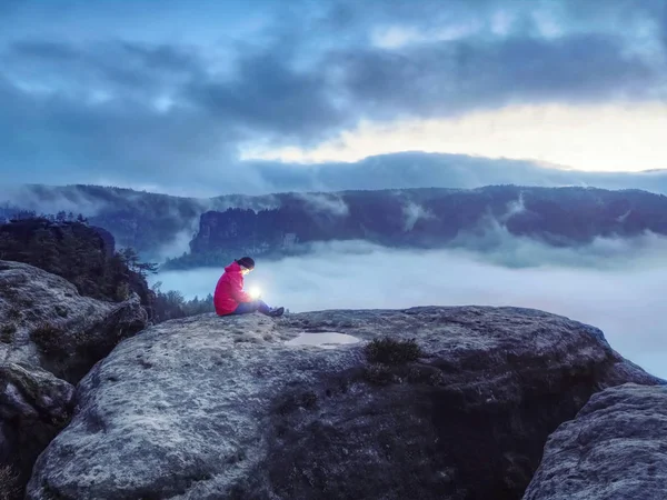 Chica sentada en la roca en la oscuridad sosteniendo en las manos símbolo de esperanza —  Fotos de Stock