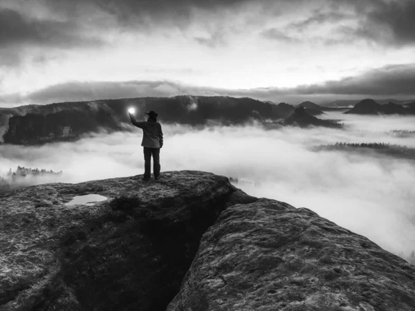 Mädchen am felsigen Rand über nebligen Wolken beleuchtete neblige Welt — Stockfoto