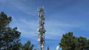 Çam ağaçlarında gizlenmiş eski tuğla evlerin üzerinde büyük telekomünikasyon antenleri olan modern kule. Pintal Vermell tepesi üzerinde dağ yolu, Mallorka adası, İspanyol Balears adaları.
