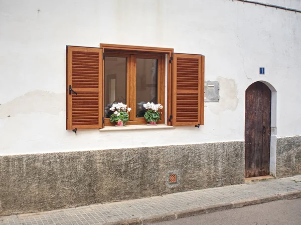 Brown shutters and flowers on the windowsill.