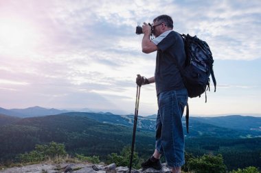 Tourist hiker photographer with backpack and poles