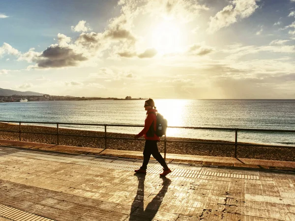 Mulher caminhante com mochila na praia do nascer do sol — Fotografia de Stock