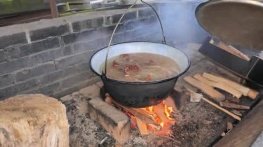 Kaynar suyu olan bir kazan. Domuz eti pişirirken eldivenli adam eli açık kazan.
