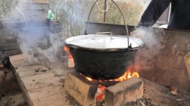 Adam asılmış kazanın altındaki açık ateşe odun koyar. Su ve et kazanda kaynatılır..