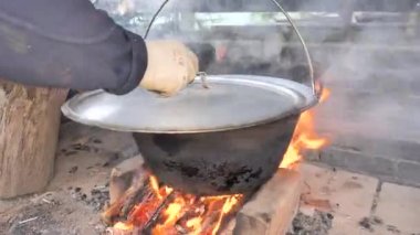 Yanan bir çaydanlıkta ahşap kaşıkla karıştırmak. Bahçe partisi için gulaş hazırlıyorum..