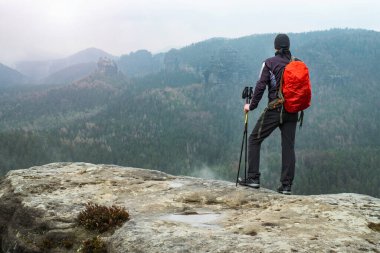 Genç gezgin erkek, yüksek irtifa yürüyüşü sırasında vadiyi ve dağları seyrediyor.