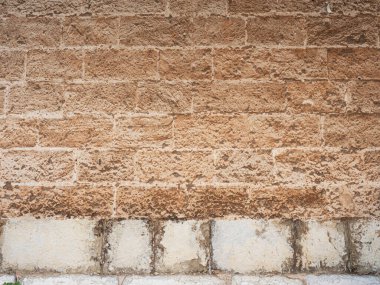 Temel kumtaşı blokları ve kaldırımlardaki taş mermer duvar, taş bloklardan yapılmış bina, mavi gökyüzüne karşı. Palma de Mallorca