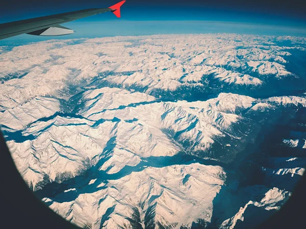 Blick Auf Einen Flugzeugflügel Über Schneebedeckten Scharfen Winterbergen — Stockfoto