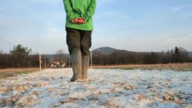 Koruyucu jelibon ayakkabılar kireç tozu içinde yürür. Yüksek lastik botlar tozlu tarladan ya da bahçeden geçiyor. Gübreyle kaplı bir alan ve dezenfeksiyon için kireç taşı öğütülmüş. Koruyucu ekipman. 