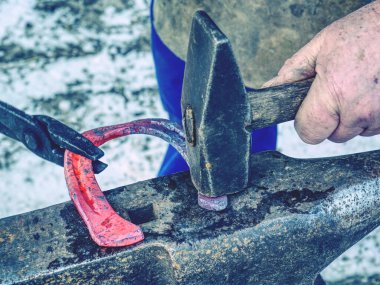 At nalını tamamla, kızgın metali çekiçle vur, demirci çalışıyor.