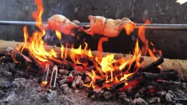 Aşçı adam, ızgara fırınında pişirilmiş mangalda tavuk kızartması üzerine baharatlı sprey sıkıyor..