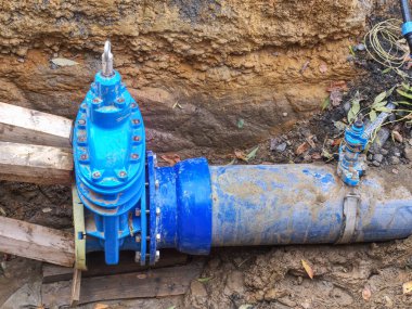 Yeraltındaki 300mm 'lik su borusunda yeni bir mavi kelebek vanası. Çelik ve Beden Eğitimi boru hattı kazıda yolun altında