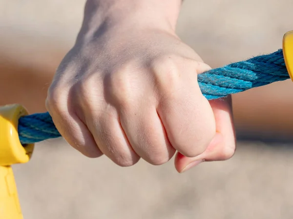 Hand hold of the rope while climbing on the training wall. Detail of rope with joint point in plastic cover.