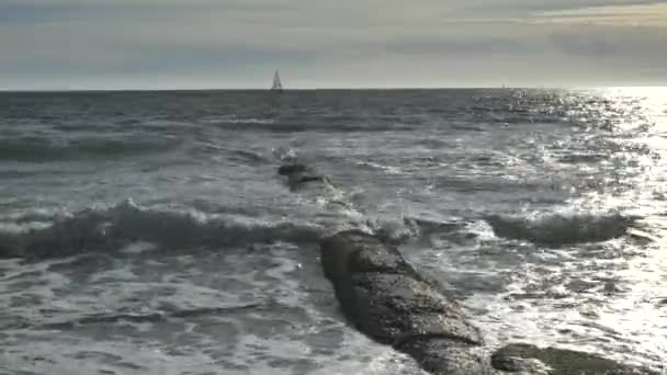 蓝色海湾岸边的石质防波堤码头与地平线上的帆船背景色相对照 — 图库视频影像