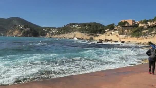 暗い髪の女性は海の岩の銀行に水を振って歩く スペインのマヨルカ島 キャンプ マルで美しいモルとビーチの景色 — ストック動画