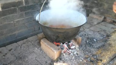 Emaye kazanı ağır dumanlı kaynar et çorbası ile. Bahçe ocağında yemek pişirmek. Bahçe partisi, arkadaş etkinliği.