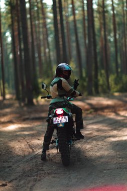 Motosikletli güzel bir kız, kıvırcık saçlı, genç bir kız, motosikletçi, motosikletçi için ekipman, güzel pozlar, çekicilik, motosiklet sürücüsü, konsept, aktif yaşam tarzı, dayanıklılık.