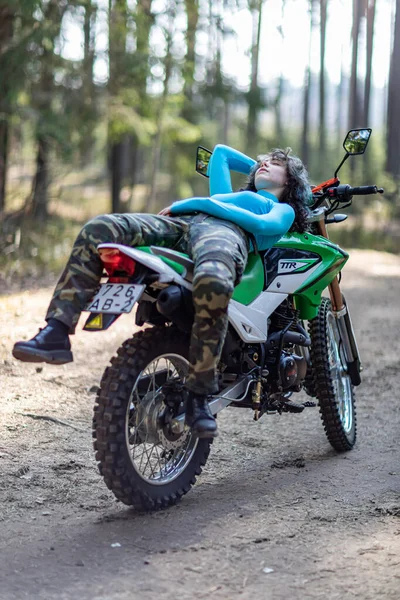 Motosikletli güzel bir kız, kıvırcık saçlı, genç bir kız, motosikletçi, motosikletçi için ekipman, güzel pozlar, çekicilik, motosiklet sürücüsü, konsept, aktif yaşam tarzı, dayanıklılık.