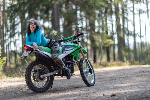 Motosikletli güzel bir kız, kıvırcık saçlı, genç bir kız, motosikletçi, motosikletçi için ekipman, güzel pozlar, çekicilik, motosiklet sürücüsü, konsept, aktif yaşam tarzı, dayanıklılık.