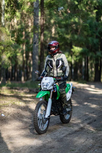 Motosikletli güzel bir kız, kıvırcık saçlı, genç bir kız, motosikletçi, motosikletçi için ekipman, güzel pozlar, çekicilik, motosiklet sürücüsü, konsept, aktif yaşam tarzı, dayanıklılık.