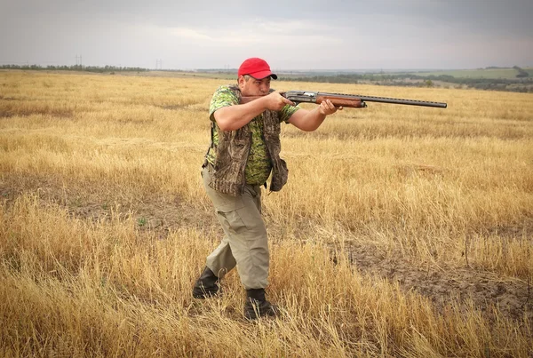 Hunter con un arma en el campo apuntando a la presa —  Fotos de Stock