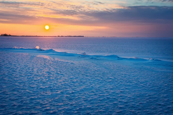 Winterlandschaft mit gefrorenem See, Rissen und Sonnenuntergang. — Stockfoto