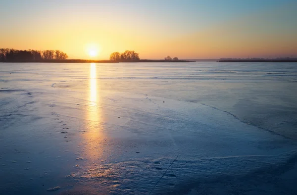 Winterlandschaft mit gefrorenem See und Feuerhimmel bei Sonnenuntergang. — Stockfoto
