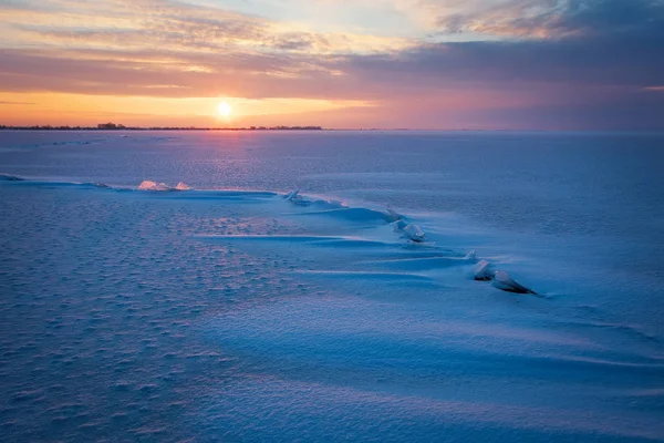 Winter landscape with frozen lake, cracks and sunset sky. — Stock Photo, Image