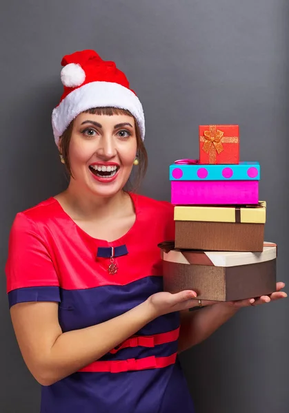 Belle fille dans la tête de Père Noël avec des boîtes-cadeaux sur fond gris . — Photo