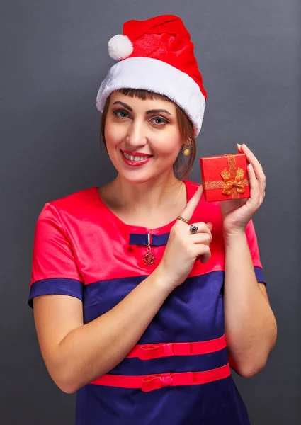Belle fille dans la tête de Père Noël avec boîte cadeau sur fond gris . — Photo