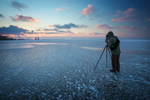 Fotograf tar en bild på solnedgången på en frusen flod — Stockfoto